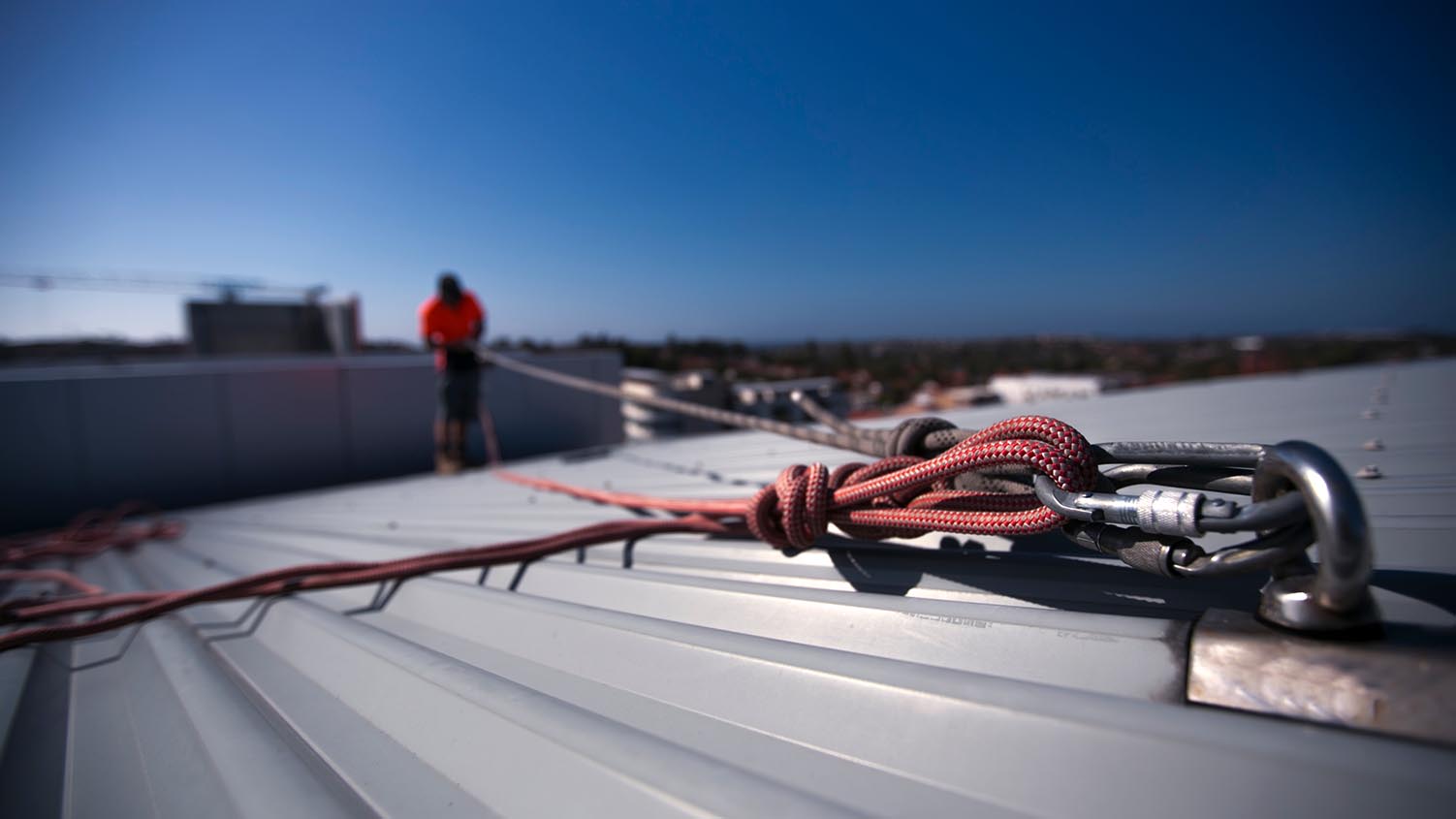 Image of an anchor point on a building with several safety harnesses attached to the anchor point.