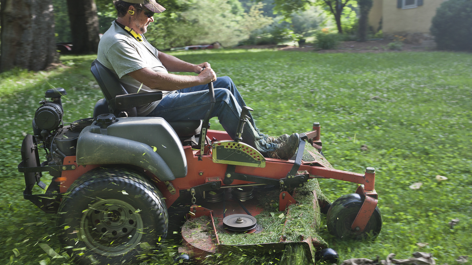Man with headphones on riding lawn mower